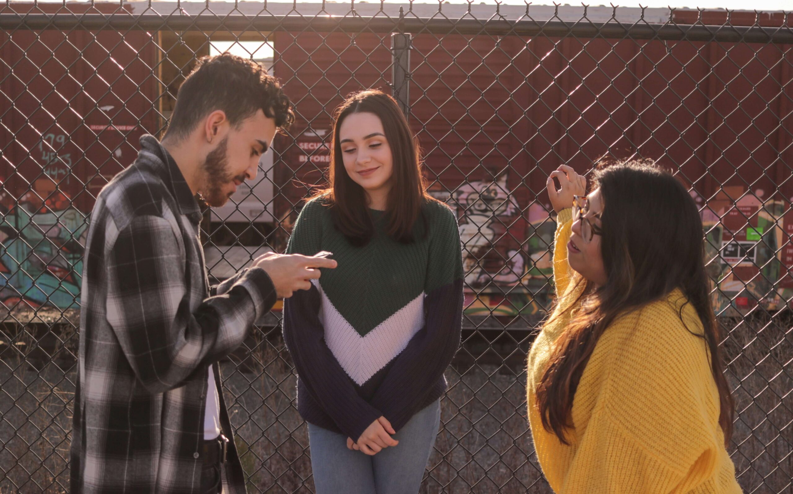 This image shows three friends talking, representing the Japanese grammar concept of extending invitations using "-ませんか" (masen ka).