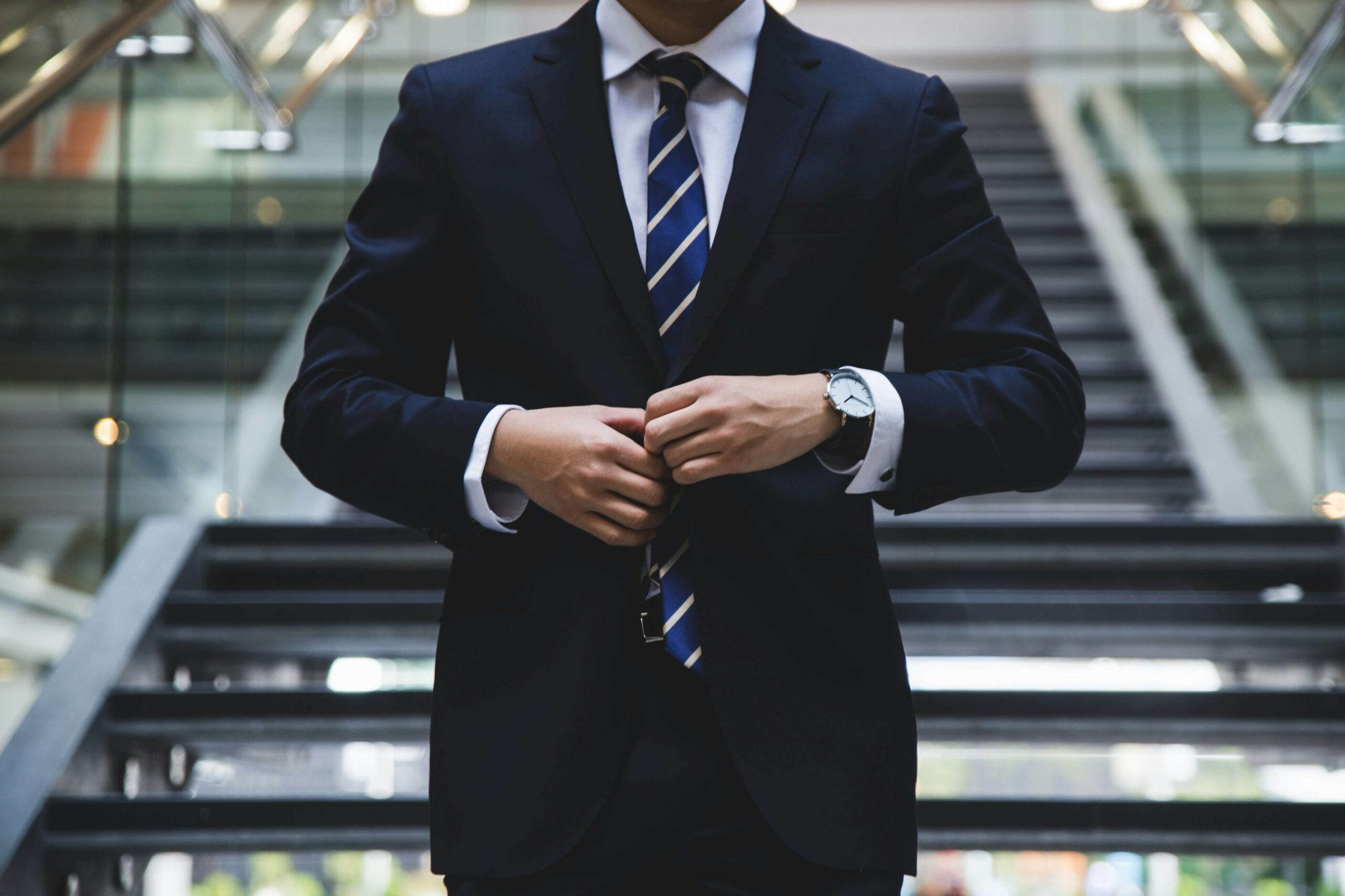 Businessman adjusting his suit, representing the concept of 'N1のN2' where the person (N2) belongs to a company (N1).
