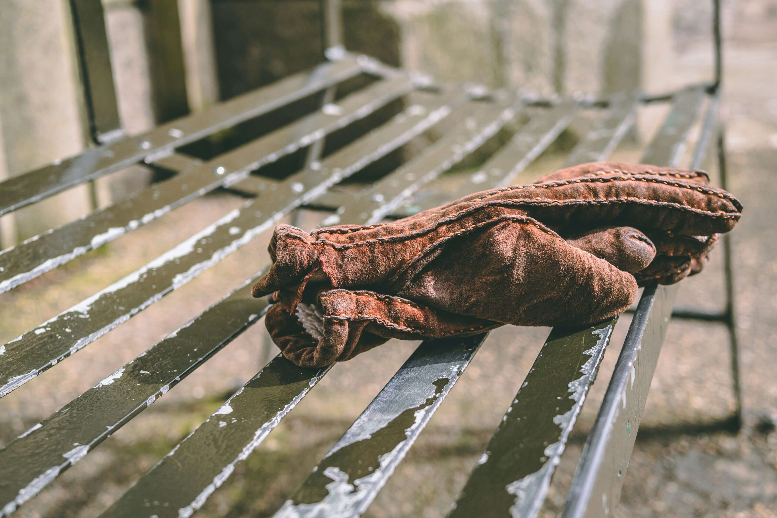 Gloves left on a bench, representing the question 'だれのてぶくろですか' (dare no tebukuro desu ka) which means 'Whose gloves are these?’