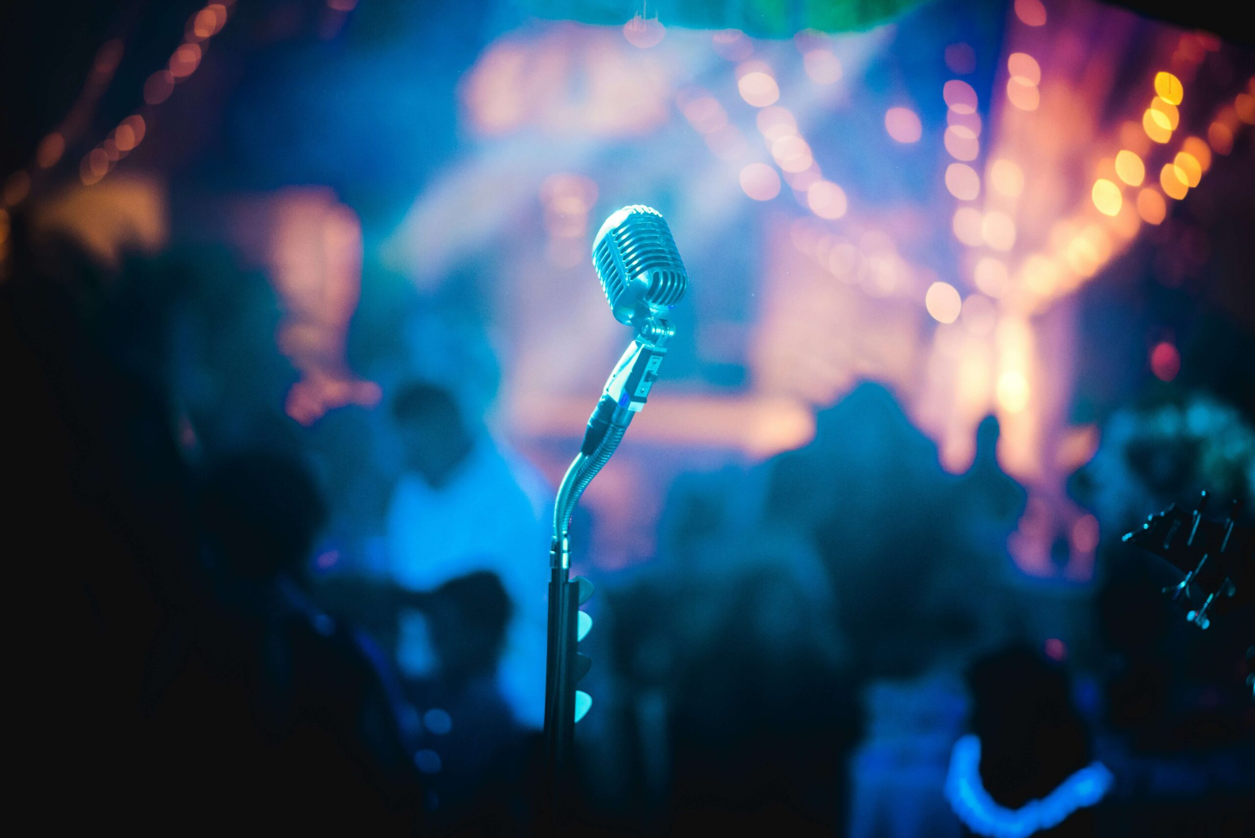 A microphone on a stage with colorful, blurred lights in the background, representing the Top 10 Japanese Songs for Language Learners.