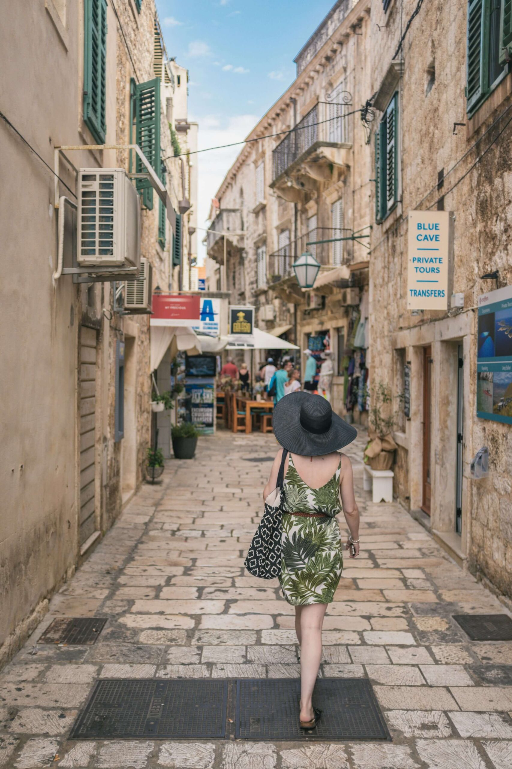 This image represents "Verb Stem + に行く" illustrated by the example: "Onna no hito ga depaato ni kaban o kai ni ikimasu" (A woman goes to a department store to buy a bag).
