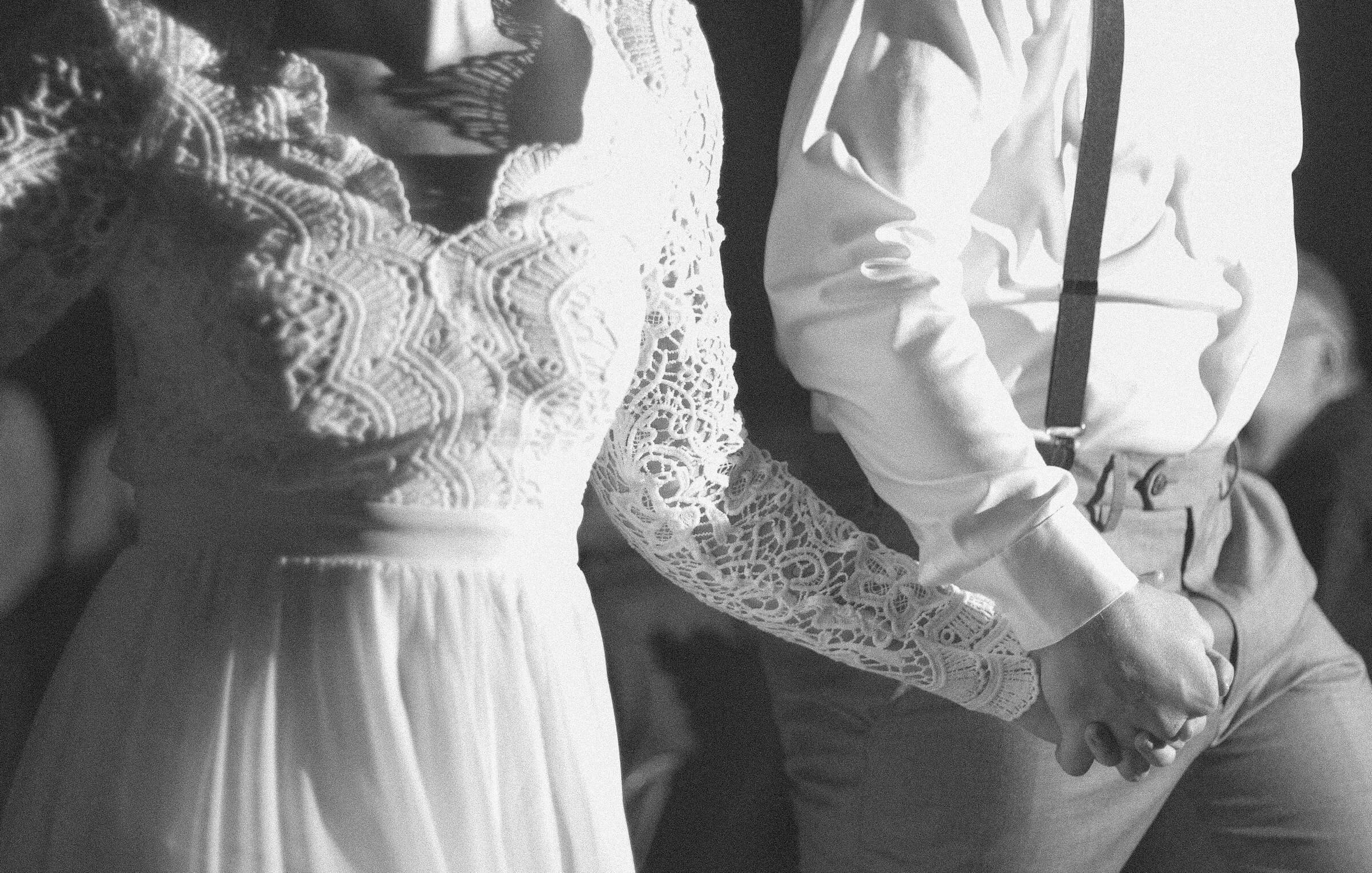 A black-and-white photo of a bride and groom holding hands, symbolizing their marriage. This image represents the concept of -ている (-teiru) to describe the result of a change in Japanese, such as being married after getting married.
