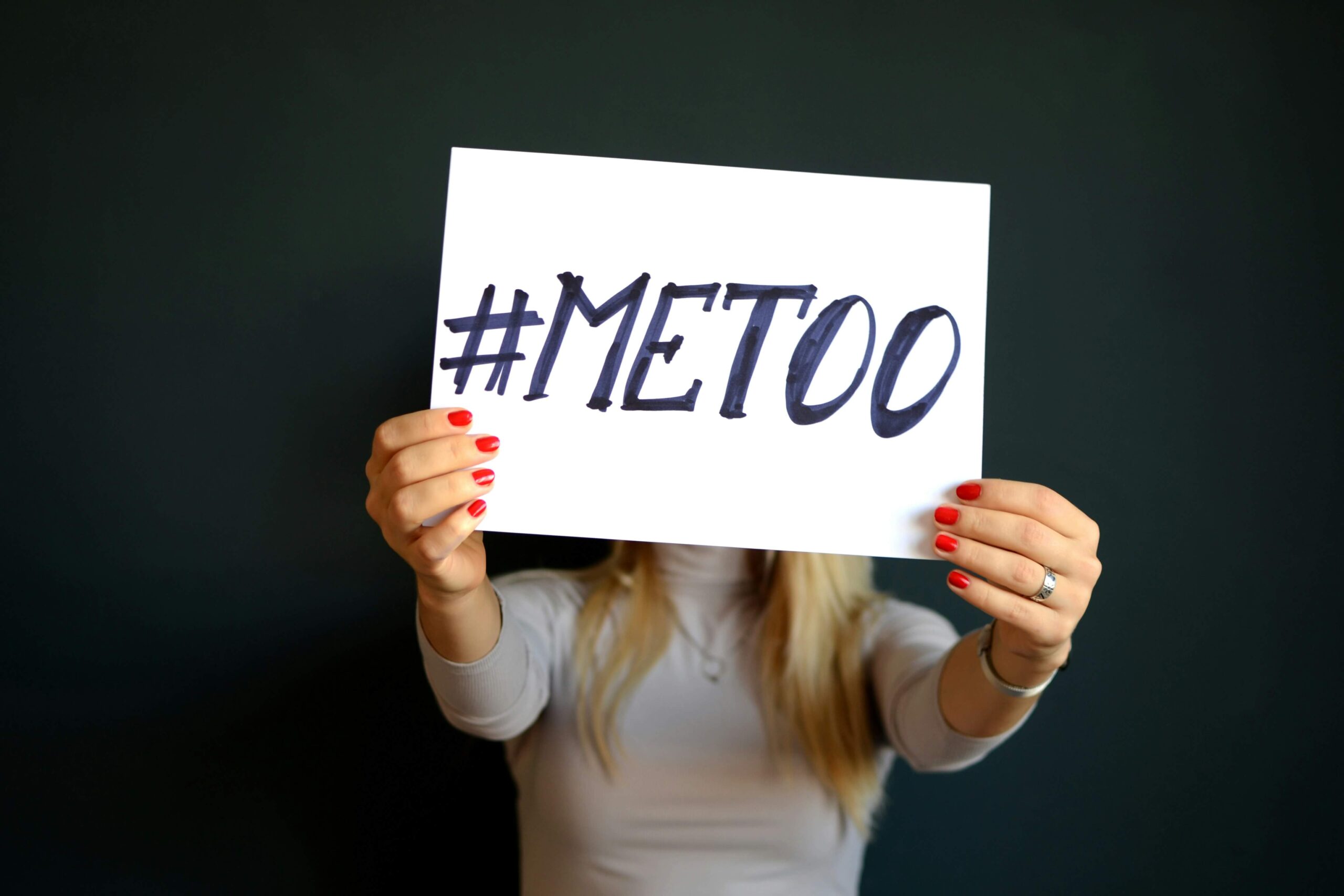 A person holding a sign with the hashtag "#METOO" written on it, symbolizing shared experiences. This image represents the concept of "も" (mo) in Genki Grammar #22, which is used to express shared attributes and activities in Japanese.
