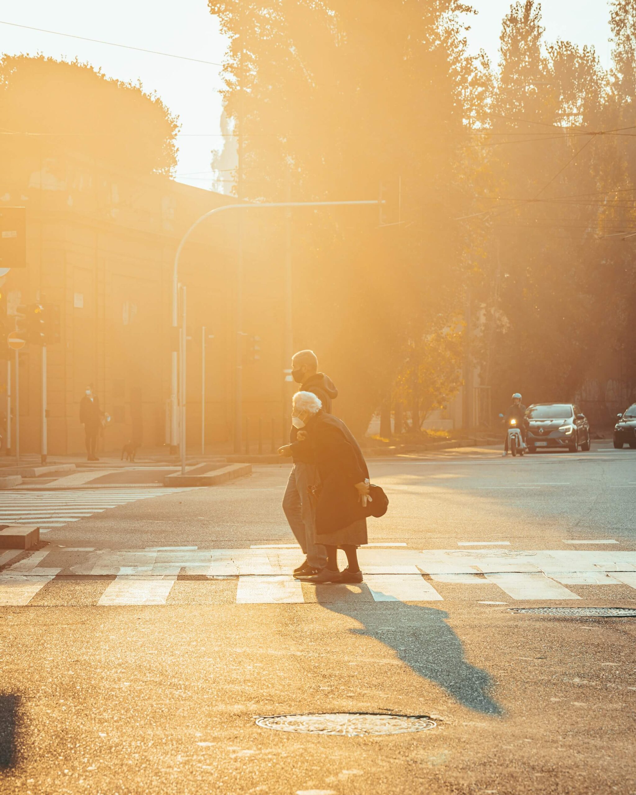 A younger person helping an elderly woman cross the street. This image represents the concept of using -ましょうか (mashouka) to offer assistance in Japanese.
