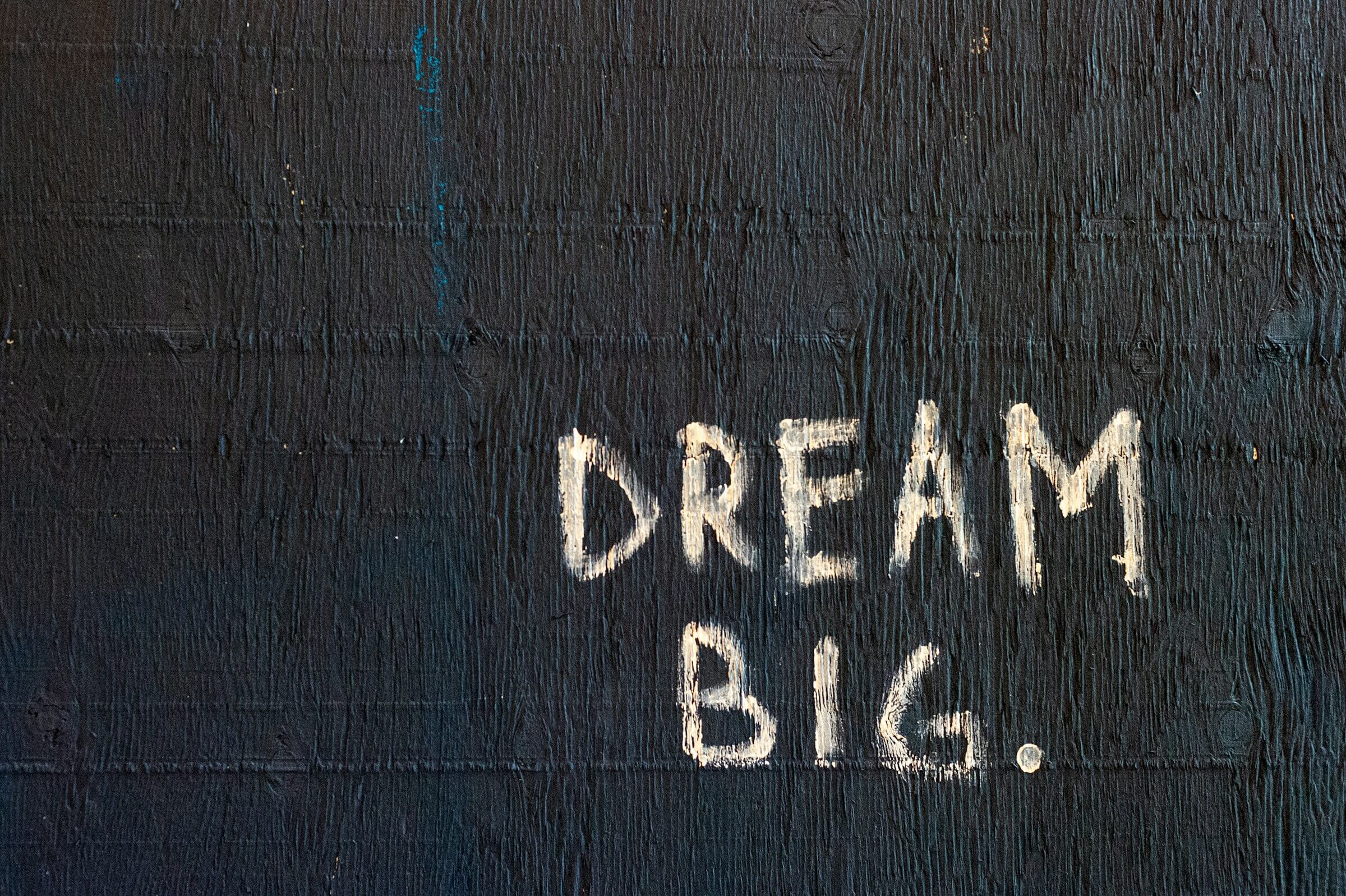 The image shows the phrase "DREAM BIG" written on a textured black surface, representing the use of と言いました (to iimashita) in Japanese, which means "said."
