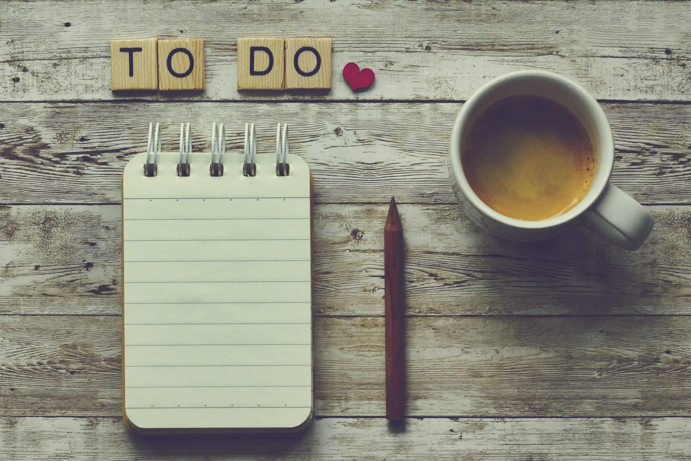 This image illustrates the concept of "-tsumorida," which is used to express intentions and plans in Japanese. The notepad and pencil symbolize making plans or listing things to do, while the coffee represents a moment of planning or setting intentions.
