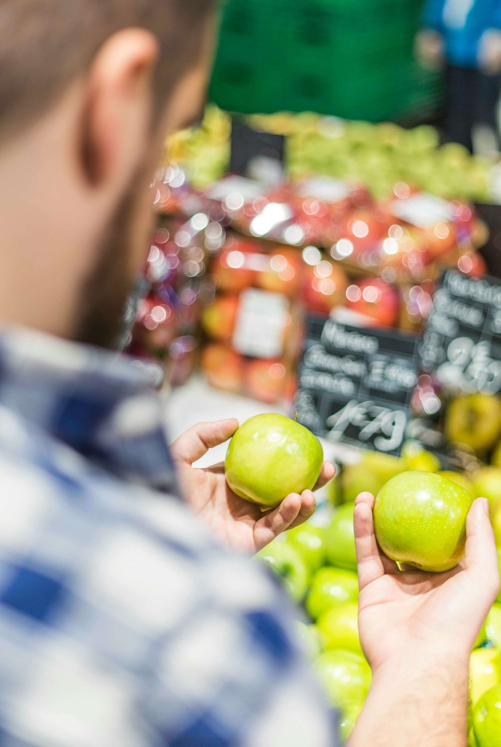 This image represents "Comparison between Two Items," illustrating a person comparing two green apples at a market.
