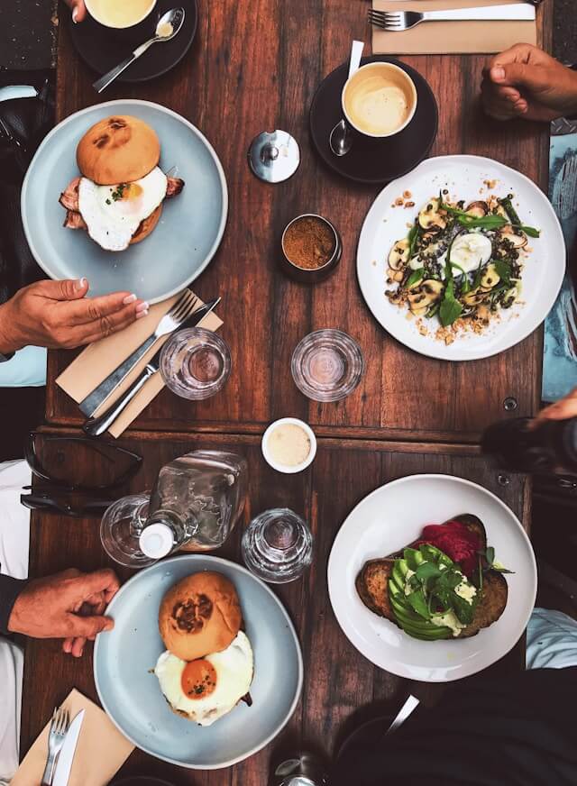 This image represents the concept of 'おごる' or 'ごちそうする' in Japanese, where people are sharing a meal together, potentially with someone treating others to the food.
